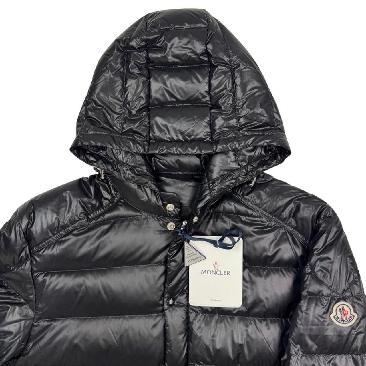 Moncler black hooded puffer jacket with logo patch and nylon material.