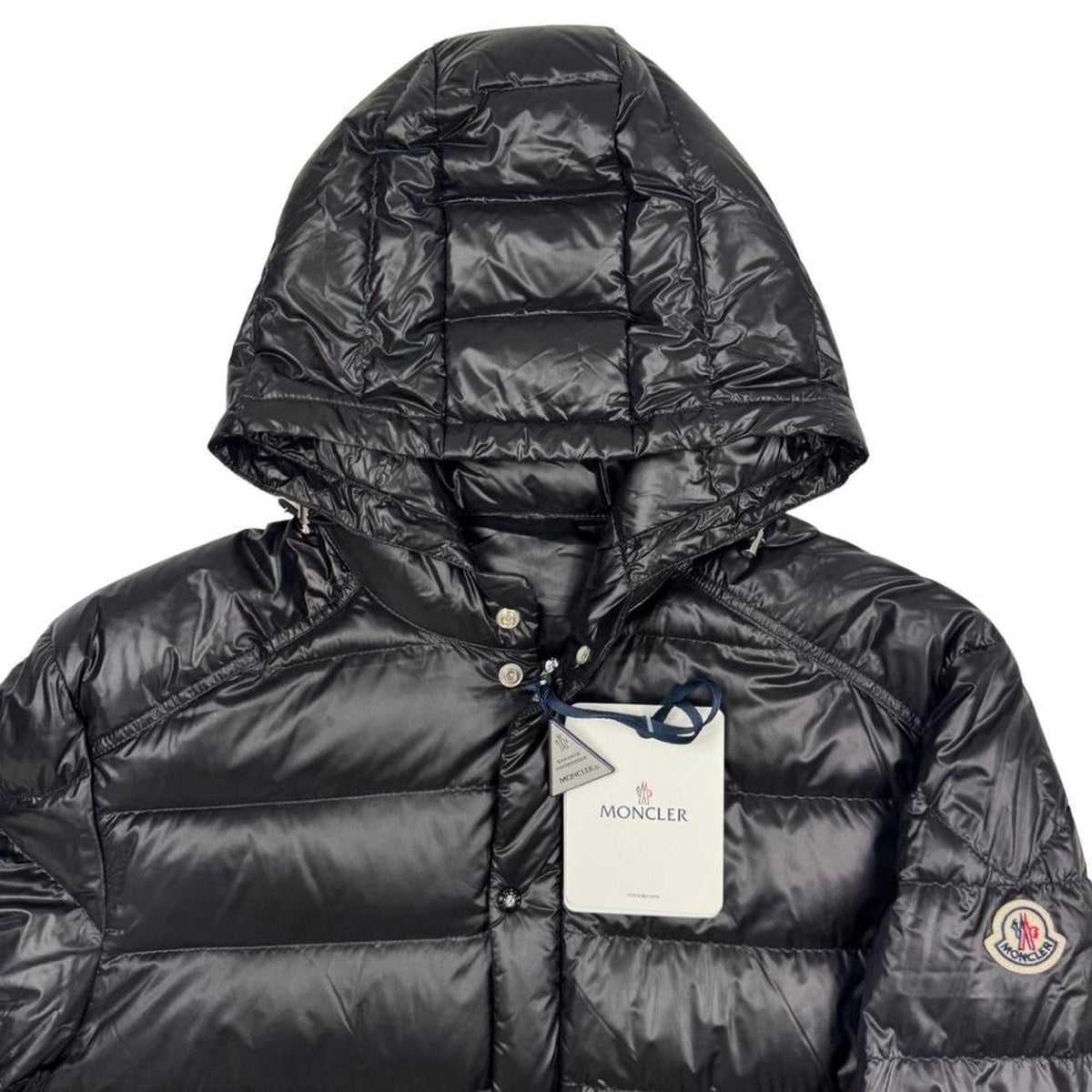 Moncler black hooded puffer jacket with logo patch and nylon material.