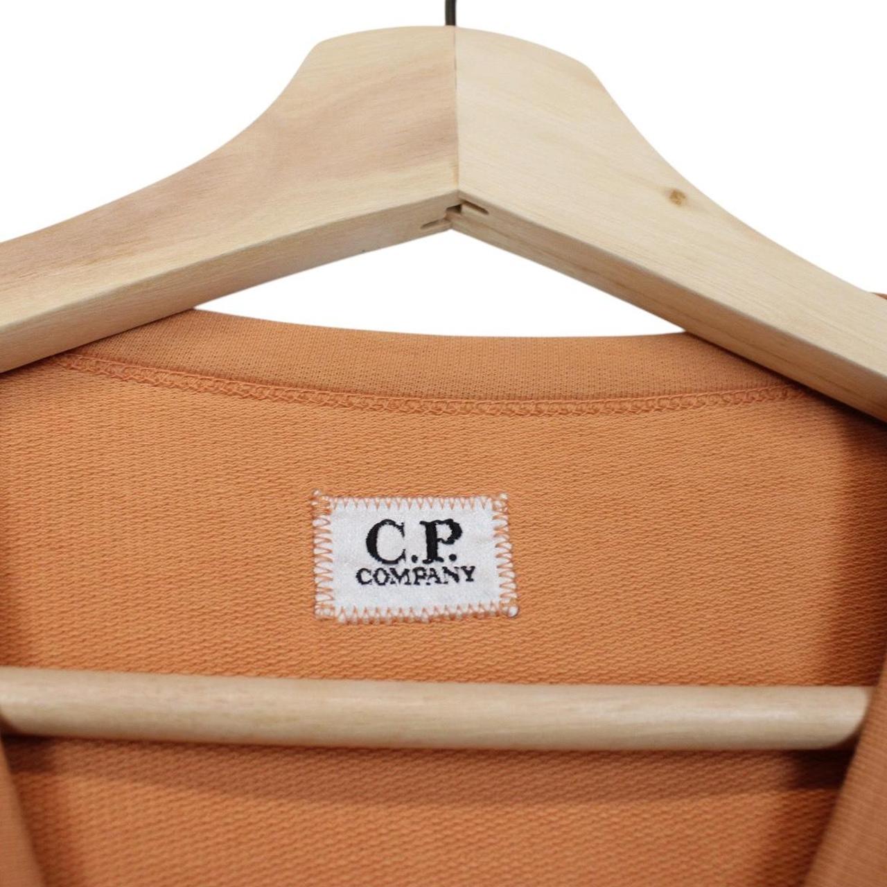 CP Company orange sweatshirt featuring goggle lens detail and soft cotton material.
