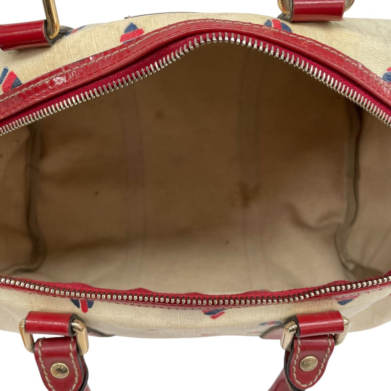 Gucci cream duffel bag with red monogram heart print and logo detailing.