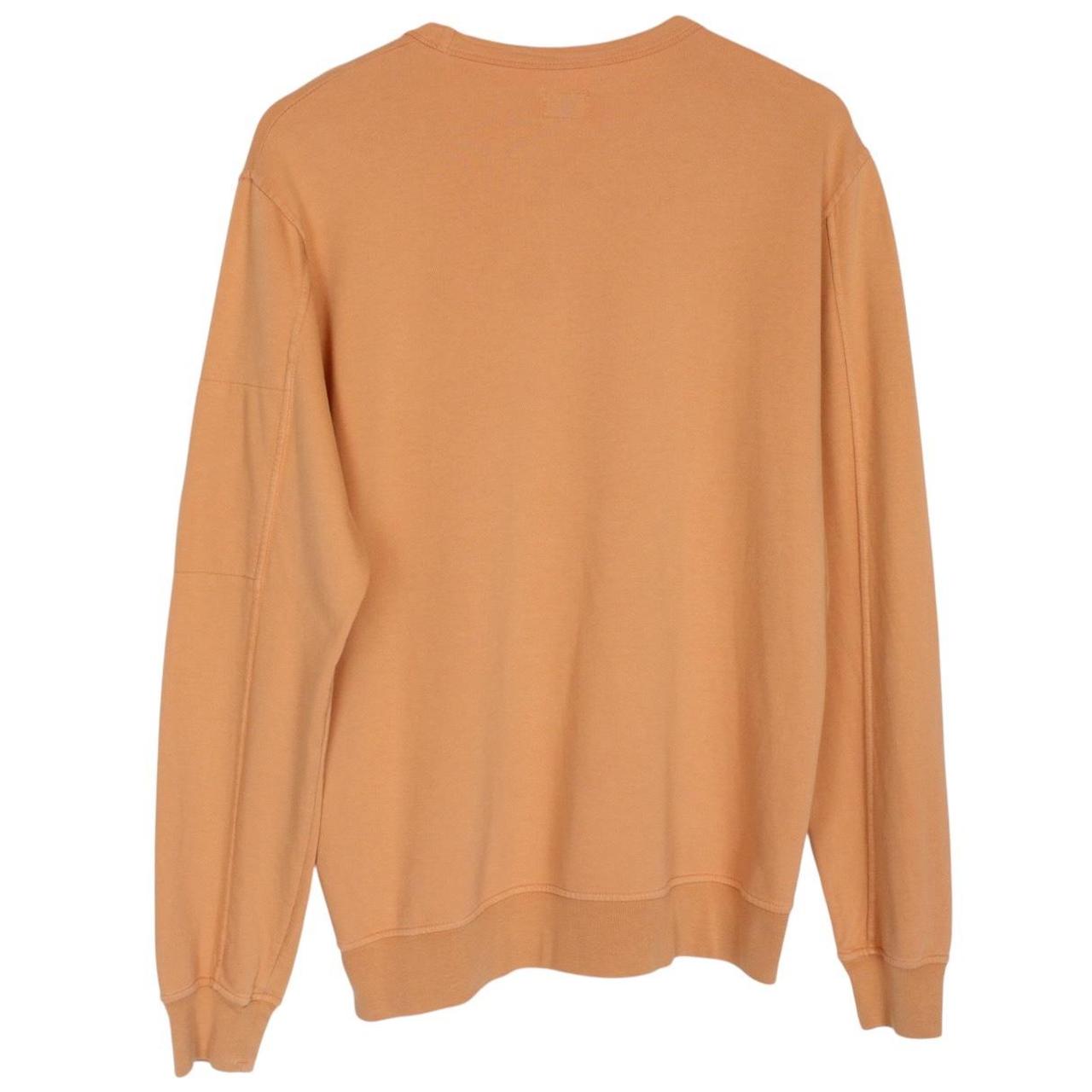 CP Company orange sweatshirt featuring goggle lens detail and soft cotton material.