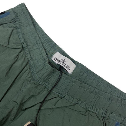 Stone Island green nylon metal trousers with logo patch and sleek finish.