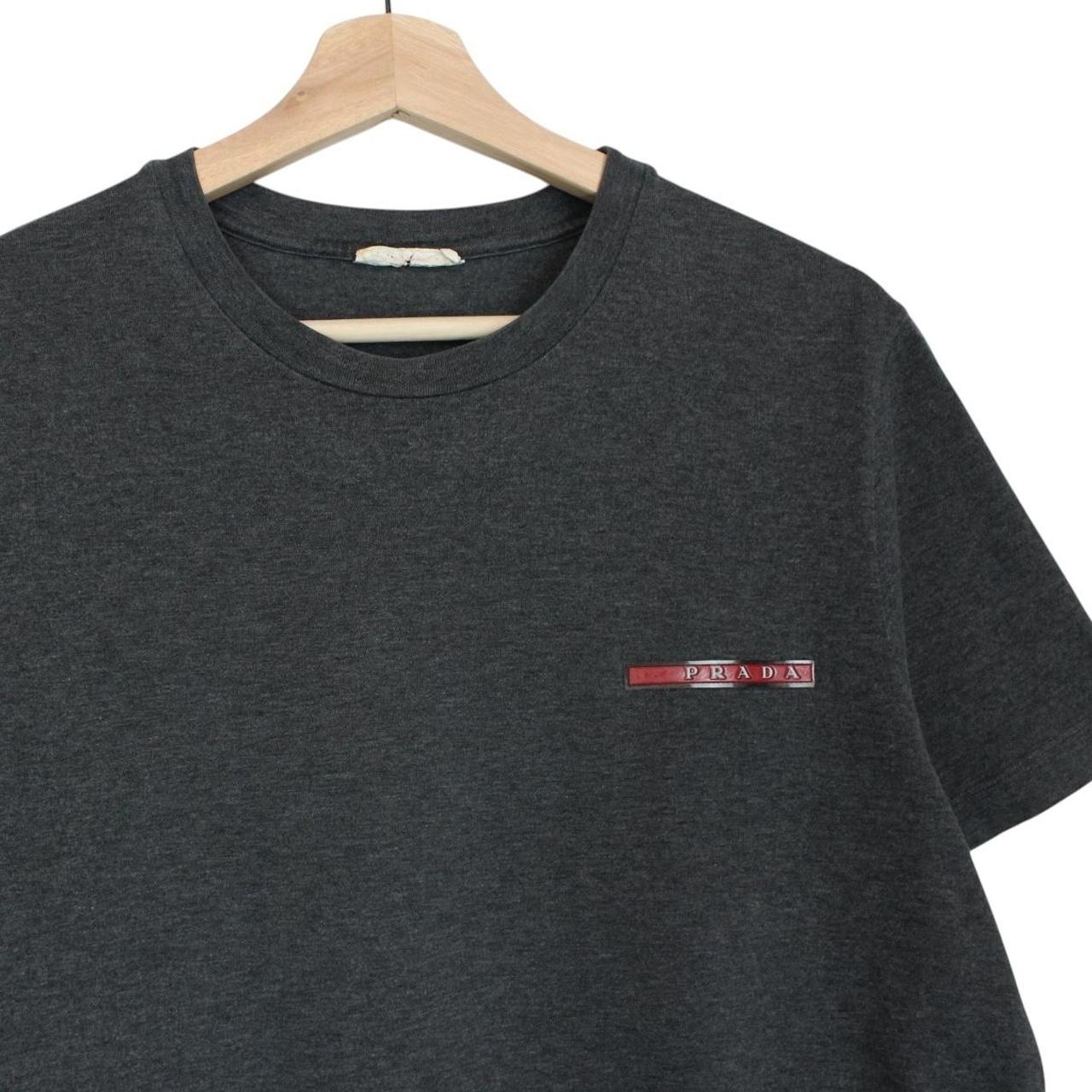 Prada grey cotton t-shirt with red logo and pocket detail, vintage style.