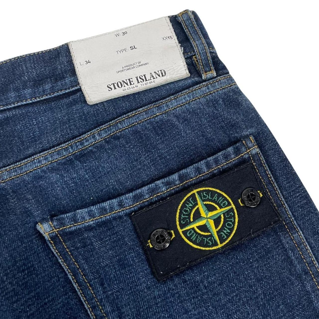 Stone Island navy blue straight jeans with logo patch and visible scuff on left knee.