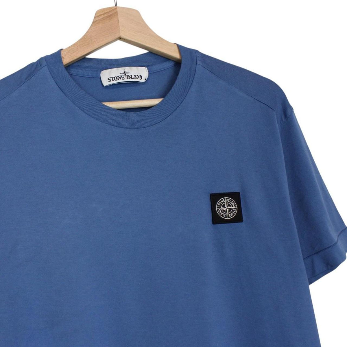 Stone Island blue short sleeve cotton t-shirt with compass logo and visible wear marks.