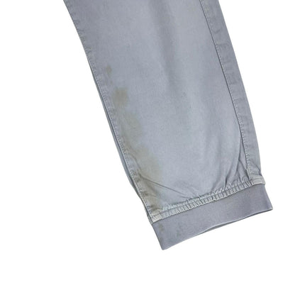 Stone Island blue cargo trousers with logo patch and RE-T fit, visible stain on left leg.