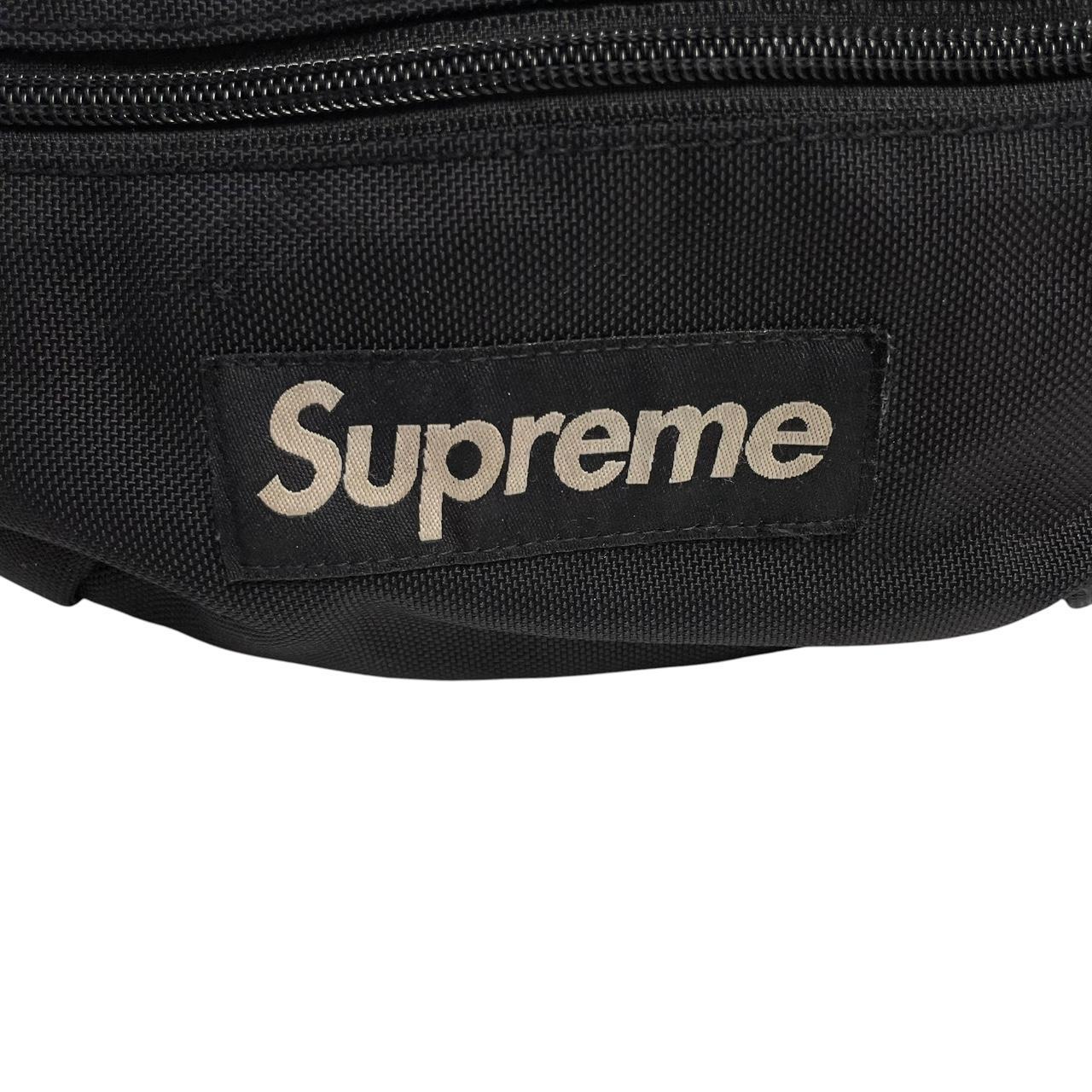 Supreme black waist bag featuring logo print and durable material.