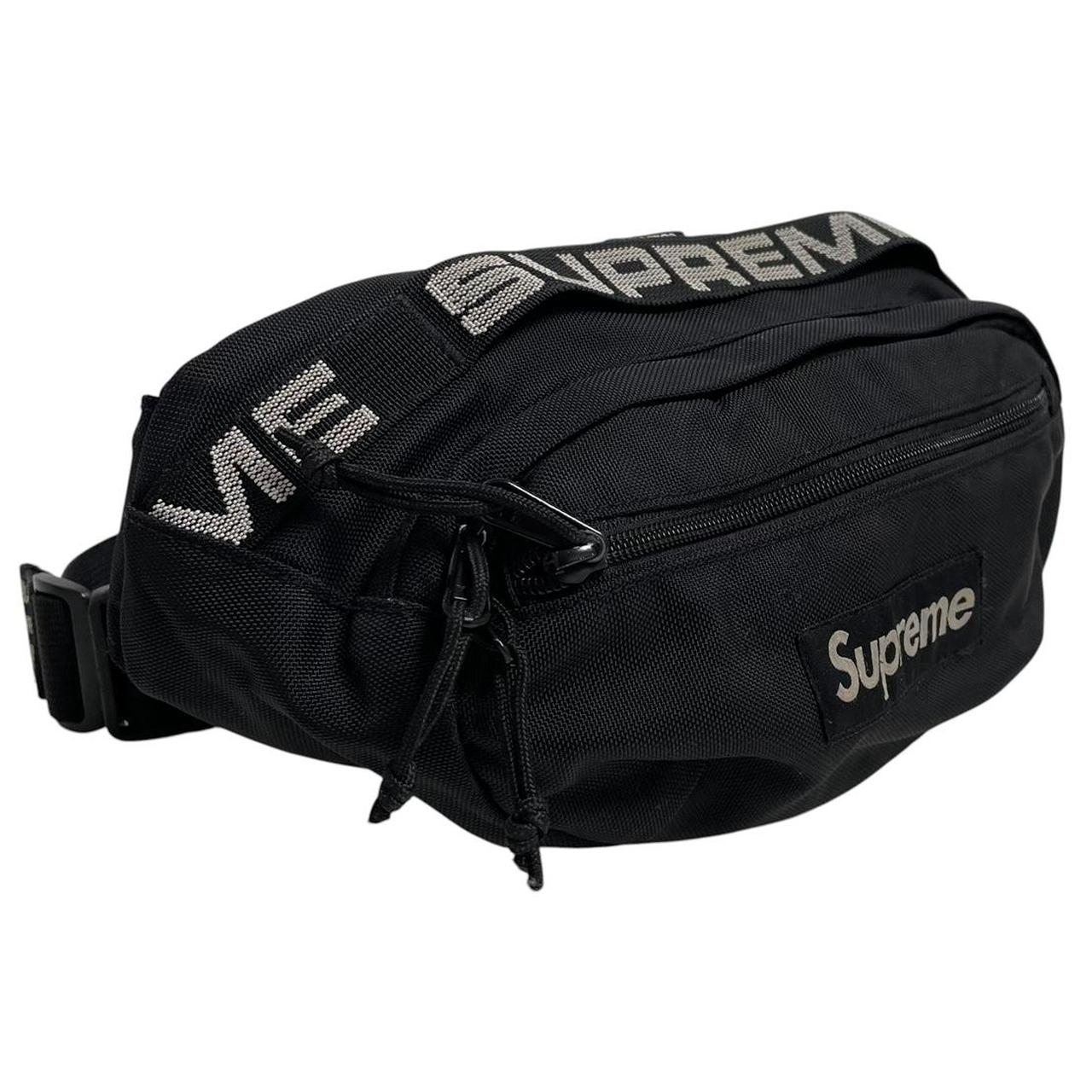 Supreme black waist bag featuring logo print and durable material.