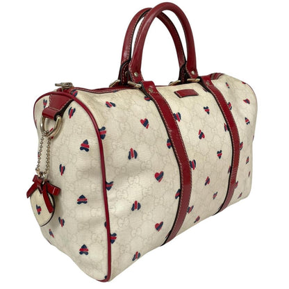 Gucci cream duffel bag with red monogram heart print and logo detailing.
