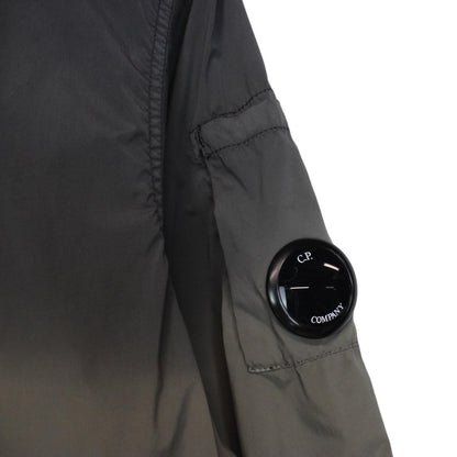 CP Company khaki green and grey jacket with shibori pattern and lens detail.