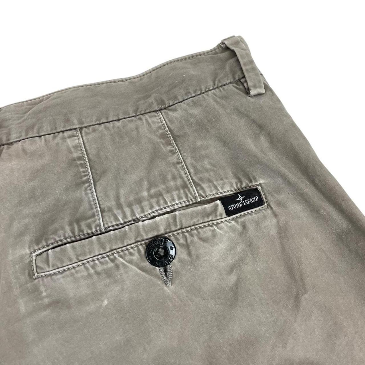 Stone Island beige slim fit cotton trousers with logo patch and visible wear marks.