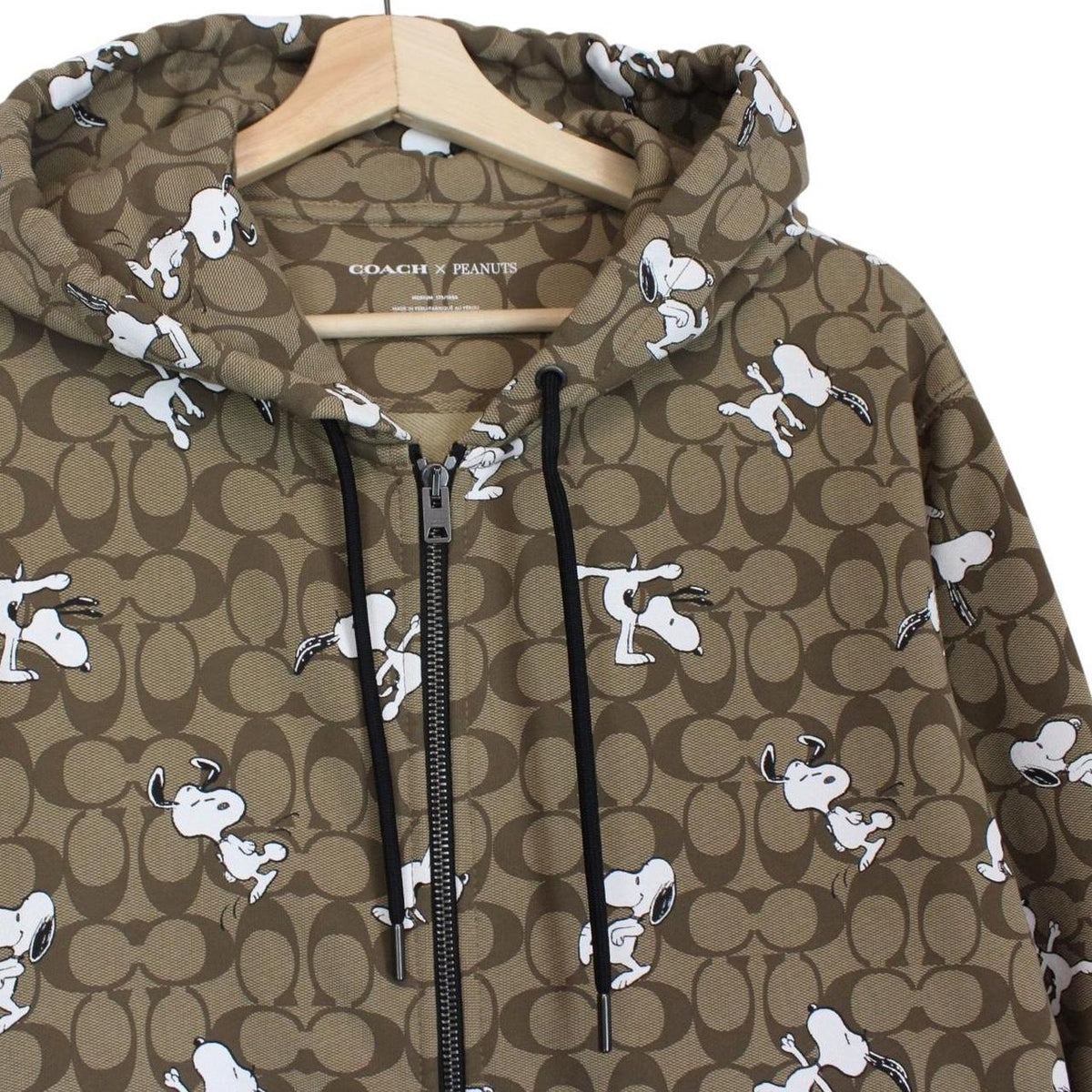 Coach brown hoodie featuring Peanuts Snoopy graphic and full zip design.