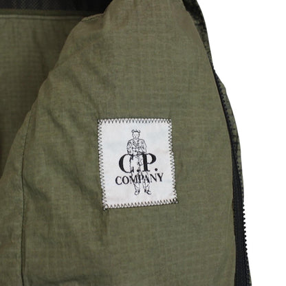 CP Company khaki green overshirt jacket with digital camouflage pattern and lens detail.