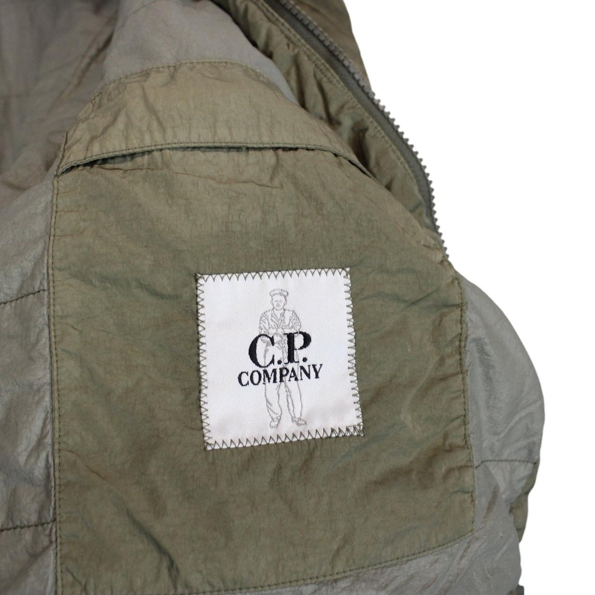 CP Company green hooded jacket with chrome detailing and logo patch on sleeve.