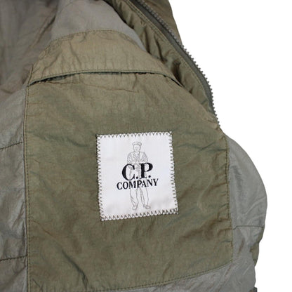 CP Company green hooded jacket with chrome detailing and logo patch on sleeve.