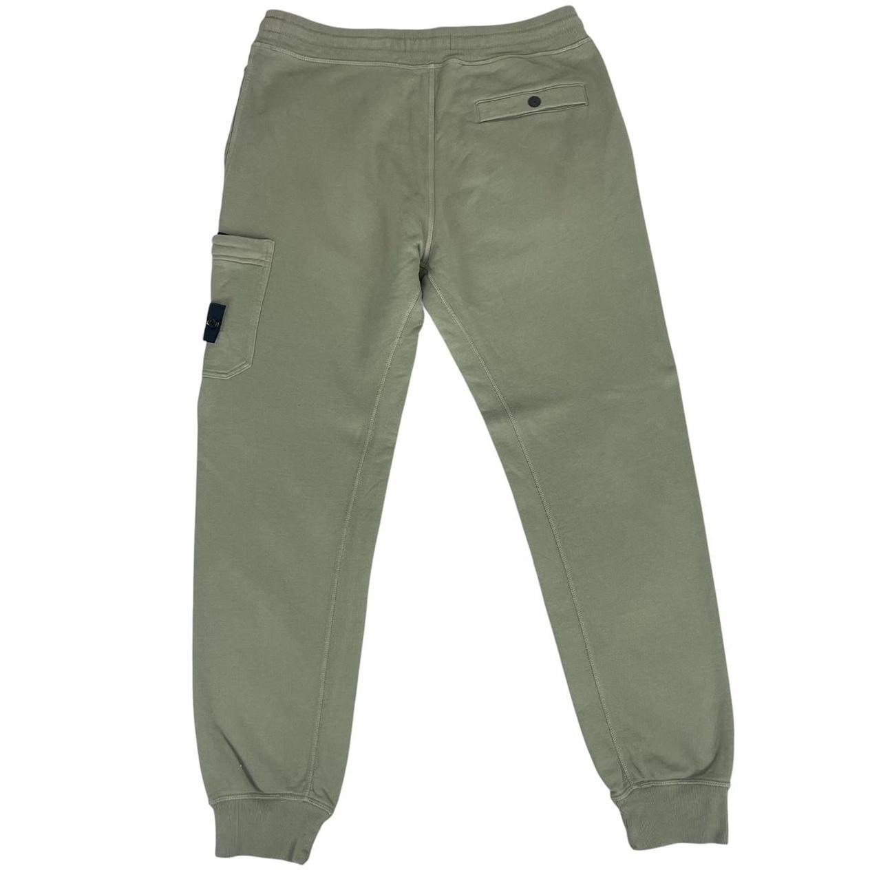 Stone Island green joggers with logo patch and cotton material, visible wear marks.